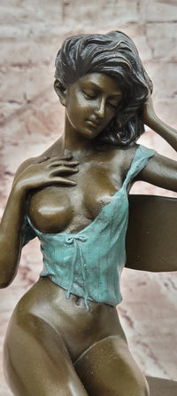 AN EROTIC BRONZE SCULPTURE OF A SEMI-NAKED WOMAN IN A CHAIR BY MILO STATUE